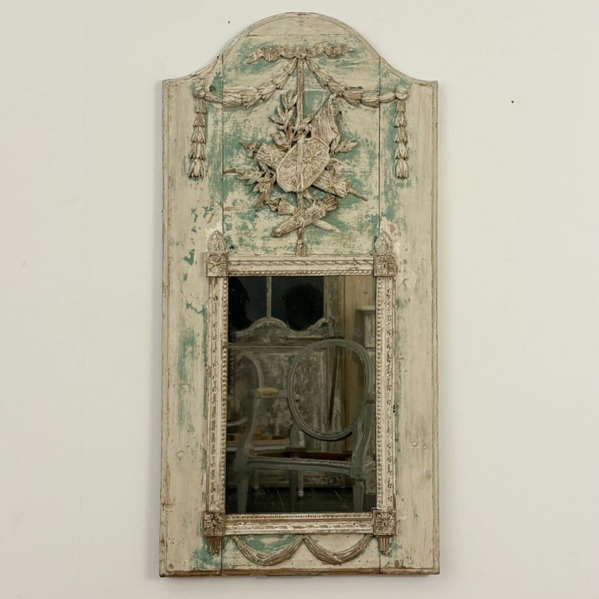 Superb small Louis XVI period trumeau mirror in carved wood decorated with warrior attributes, originally painted. - JAA