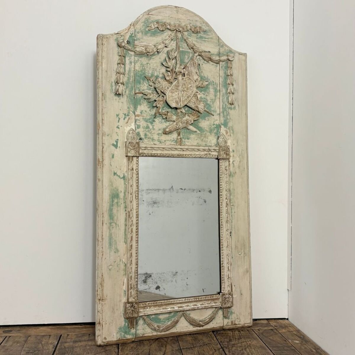 Superb small Louis XVI period trumeau mirror in carved wood decorated with warrior attributes, originally painted. - JAA