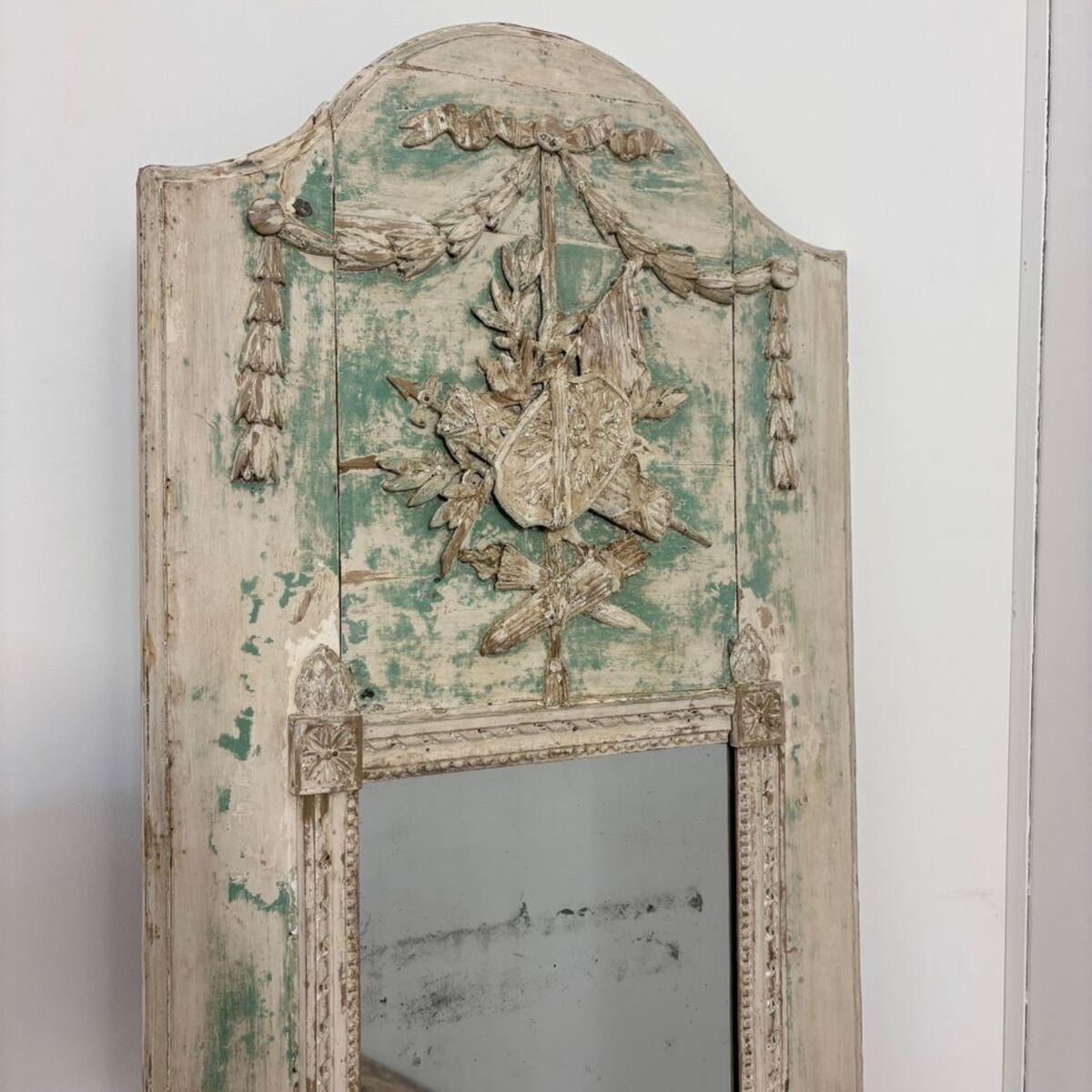 Superb small Louis XVI period trumeau mirror in carved wood decorated with warrior attributes, originally painted. - JAA