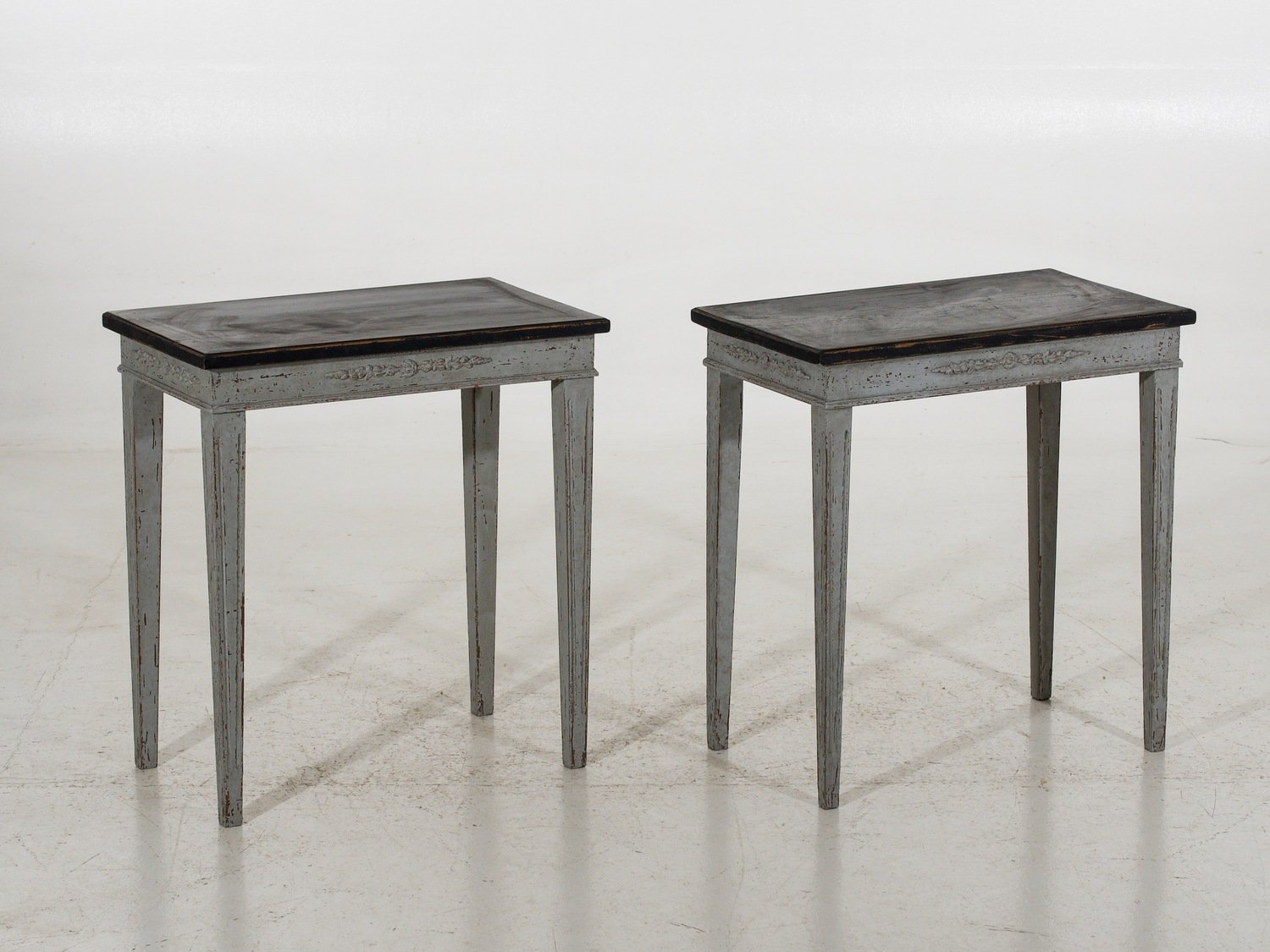 Pair of freestanding side tables with sweet carvings and black top, late 19th Century. - JAA